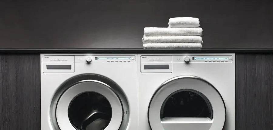 Modern laundry room with stacked white towels on silver front-load washer and dryer