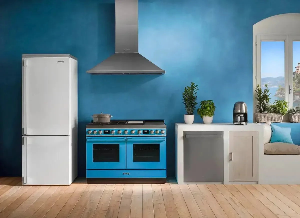 Vibrant blue dual oven range with stainless hood in modern kitchen with white fridge and wood floors
