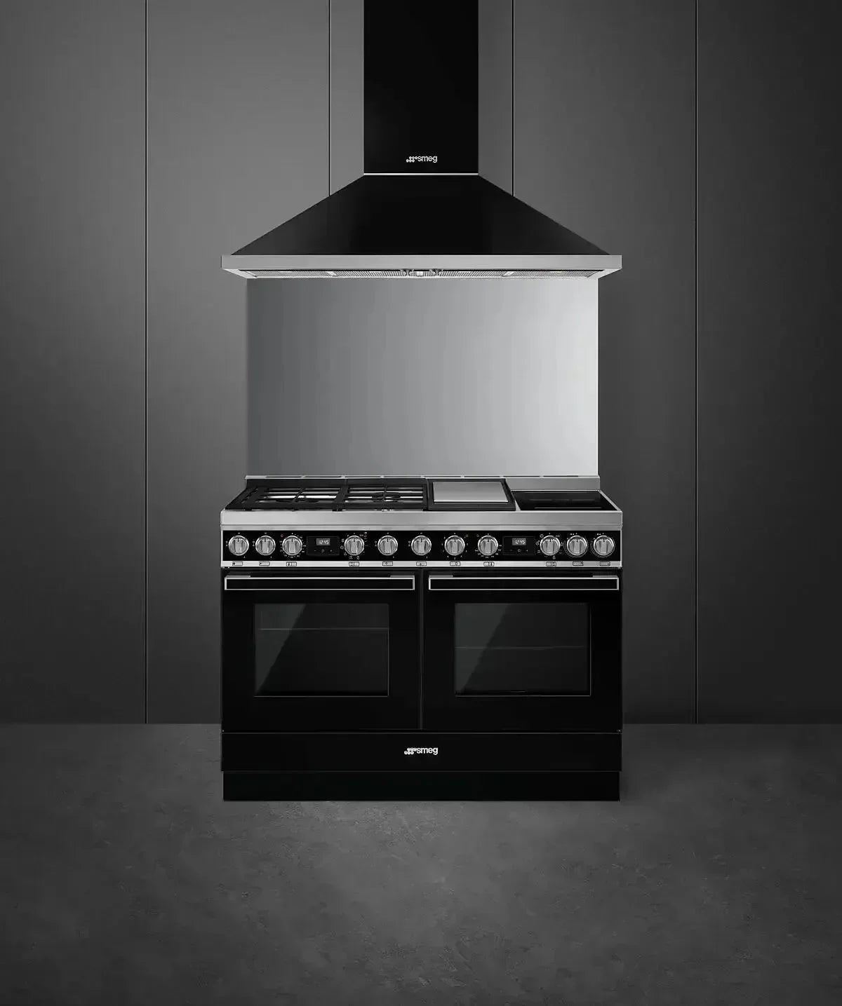 Smeg black dual oven range with gas cooktop and matching hood in modern kitchen