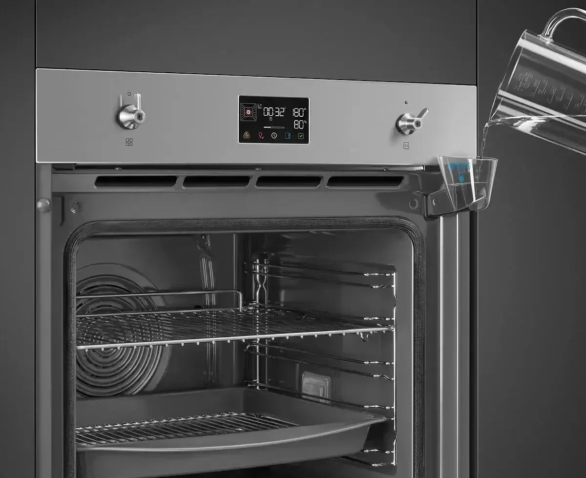 Stainless steel oven with digital display and water being poured into steam tray for baking