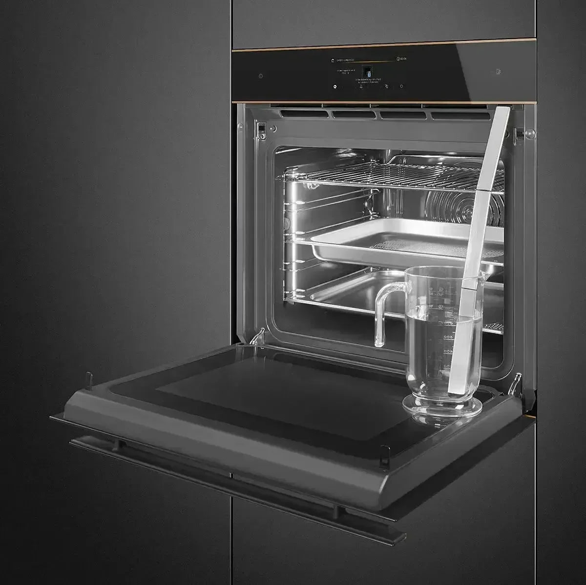 Modern built-in oven with open door, interior racks, baking tray, and measuring cup on door