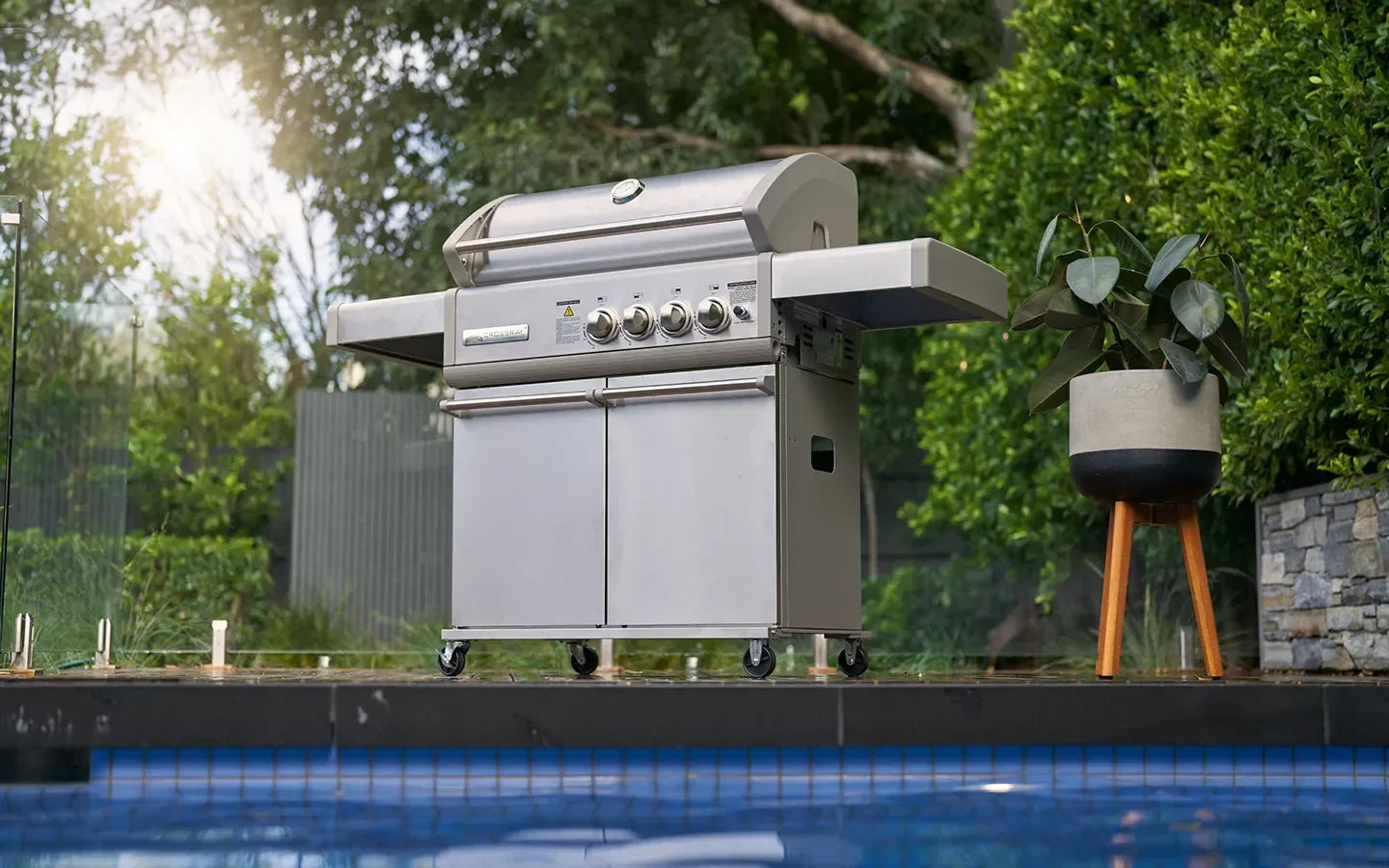 Stainless steel gas grill by poolside, perfect for outdoor cooking and backyard entertaining.