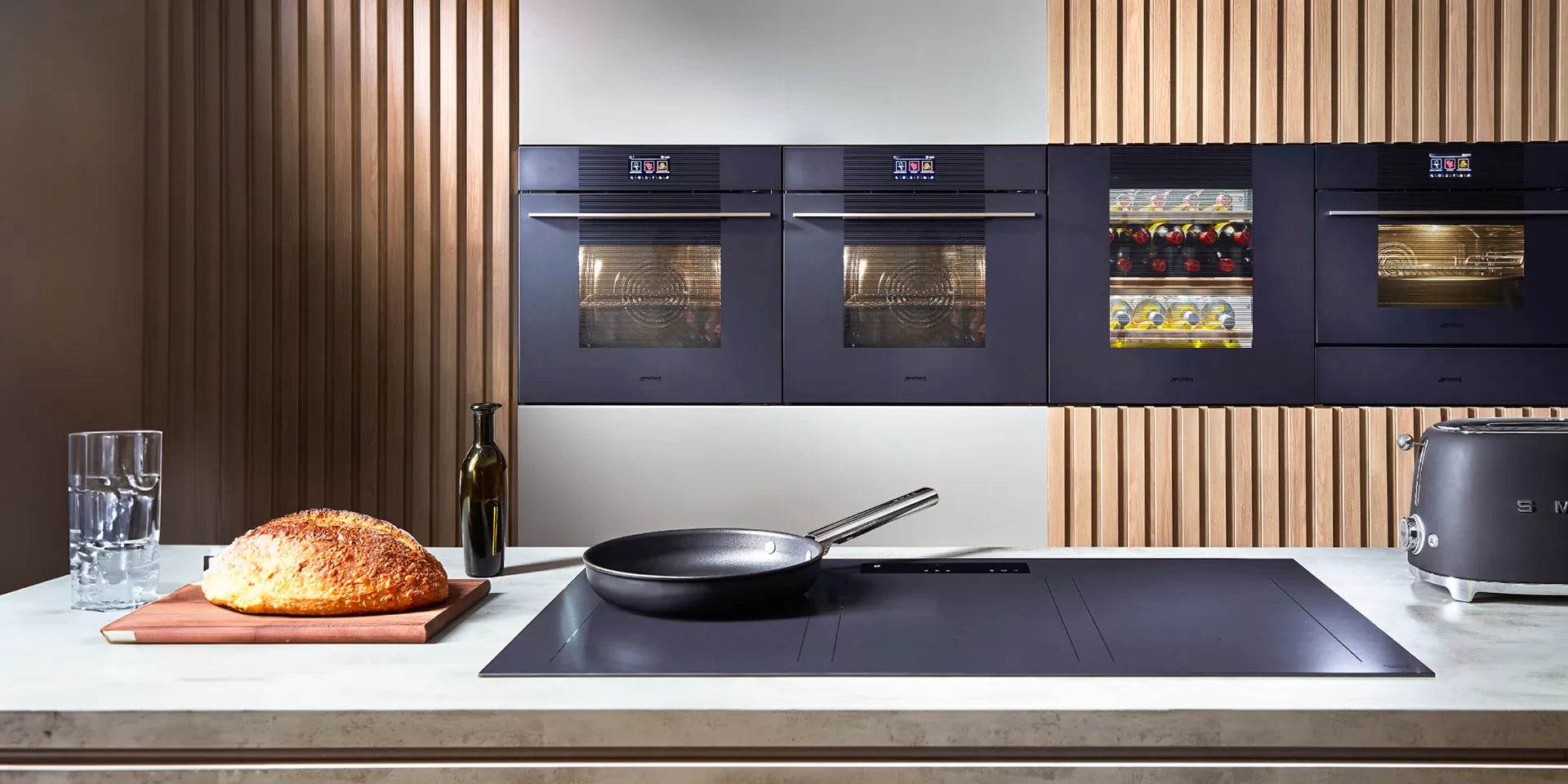 Modern kitchen with built-in ovens, wine cooler, induction cooktop, and fresh bread on counter