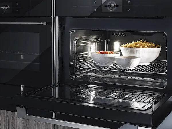 Black built-in oven with glass door, baking dishes inside, modern kitchen appliance
