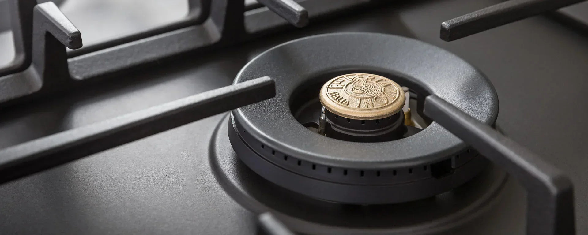Close-up of a luxury gas stove burner with a brass cap and matte black grates