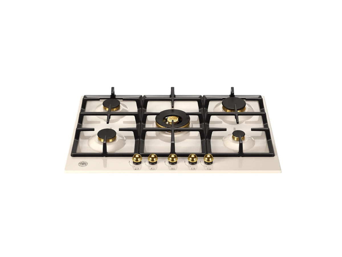 Cream gas cooktop with black cast iron grates and gold control knobs