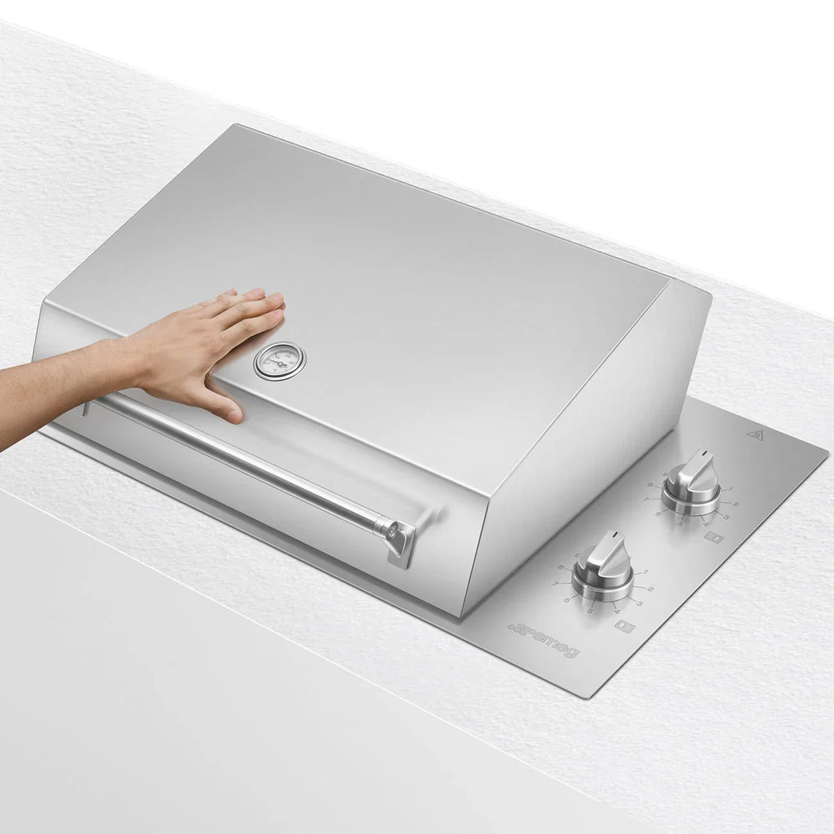 Hand touching the lid of a Smeg 90cm built-in electric barbecue