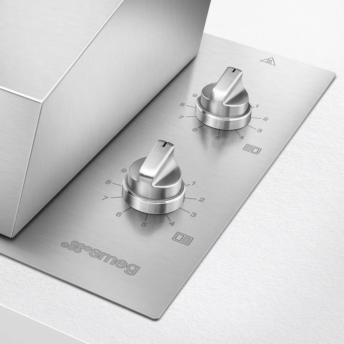 Close-up of the stainless steel control panel and knobs of a Smeg built-in electric barbecue.