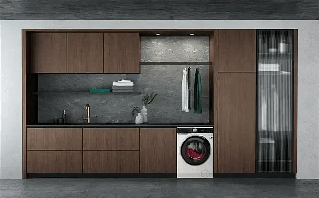 Modern laundry room with sleek wood cabinetry, built-in washer, and gray stone backsplash