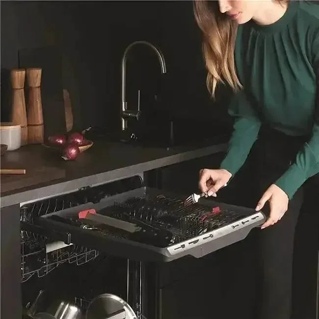 Woman loading sleek black dishwasher in modern kitchen with designer appliances