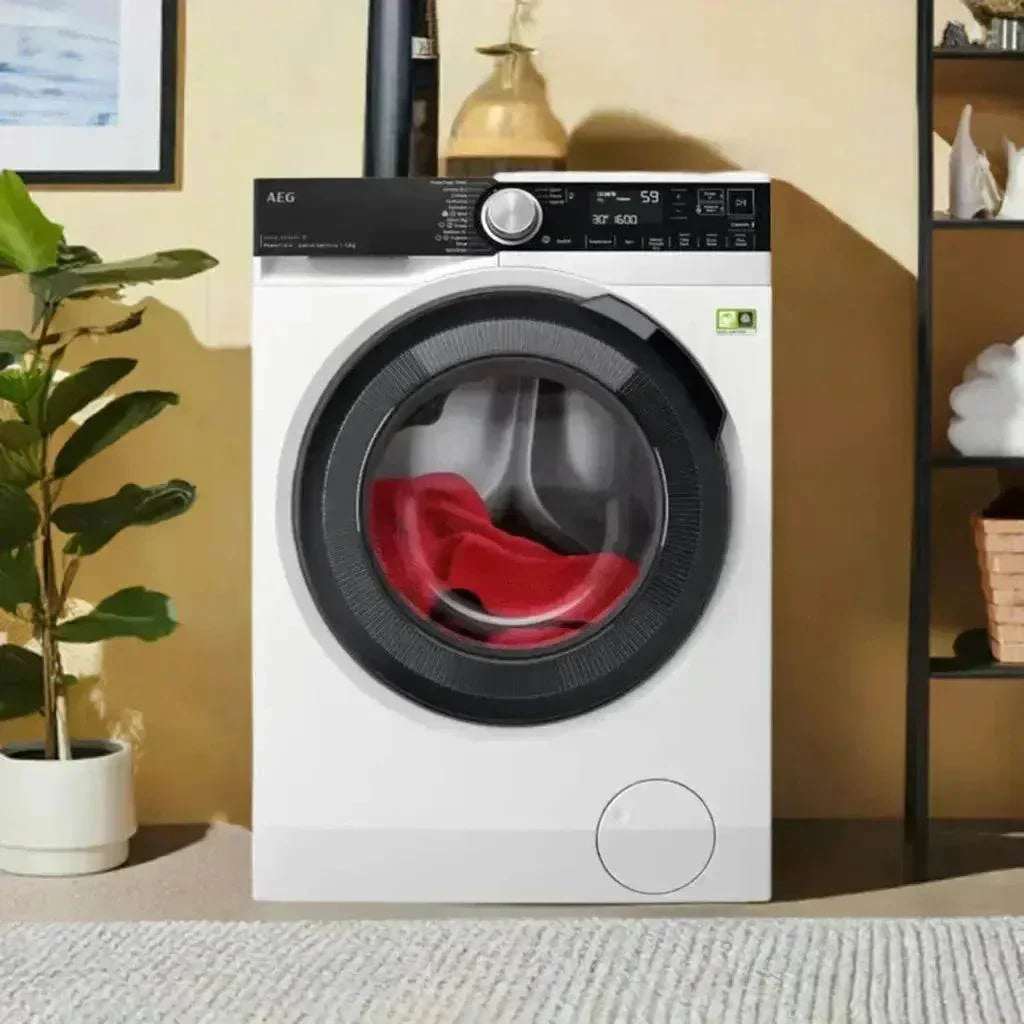 AEG front load washing machine with red laundry inside, modern kitchen appliance