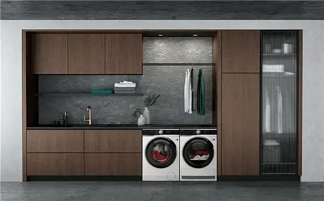 Modern laundry room with sleek washer and dryer, wood cabinets, and gray stone backsplash