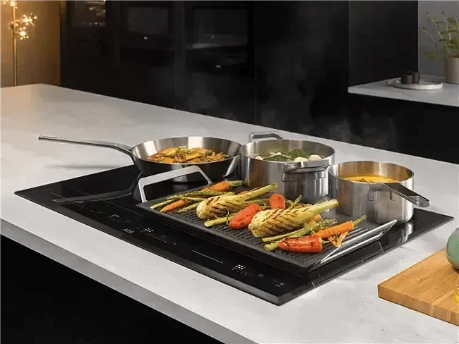 Falcon premium European Glass Black Upright 1100mm Induction Cooker with pots and grilled vegetables on a modern kitchen countertop.