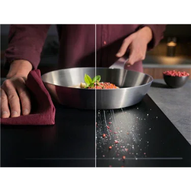 Stainless steel frying pan with herbs and spices on modern induction cooktop, hands preparing meal