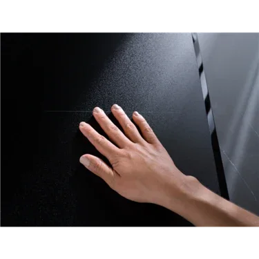 Hand touching sleek black appliance surface, showcasing modern kitchen design