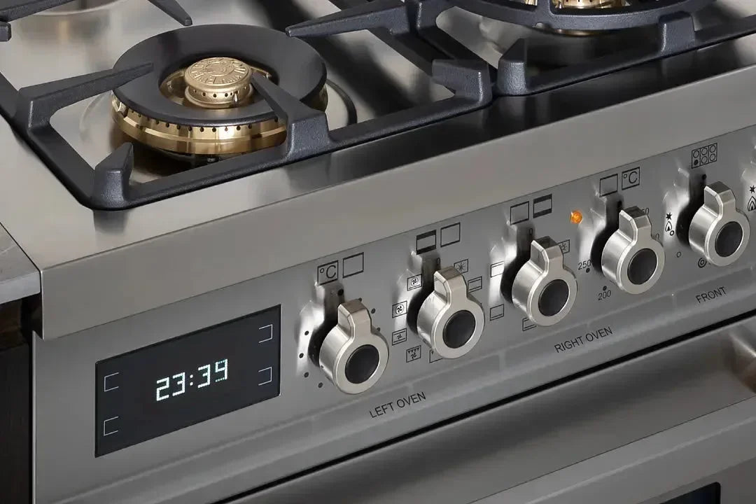 Stainless steel gas range with digital clock and oven controls, featuring brass burners and designer kitchen appliance styling