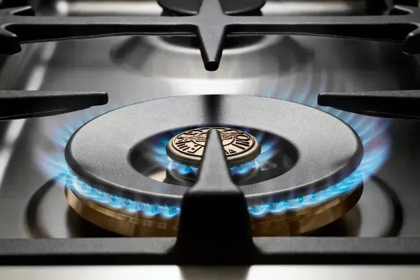 Blue flame gas burner on stainless steel cooktop, designer kitchen appliance