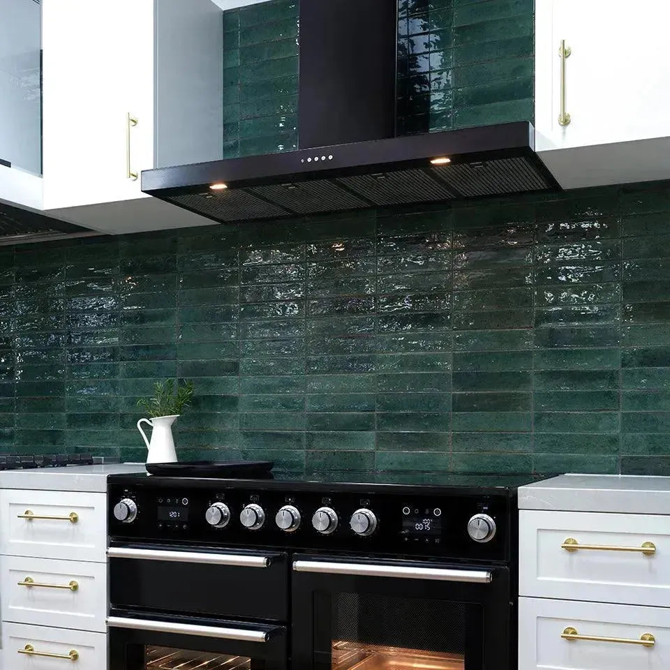 Black range cooker with double ovens under sleek hood, set against green tile backsplash in modern kitchen