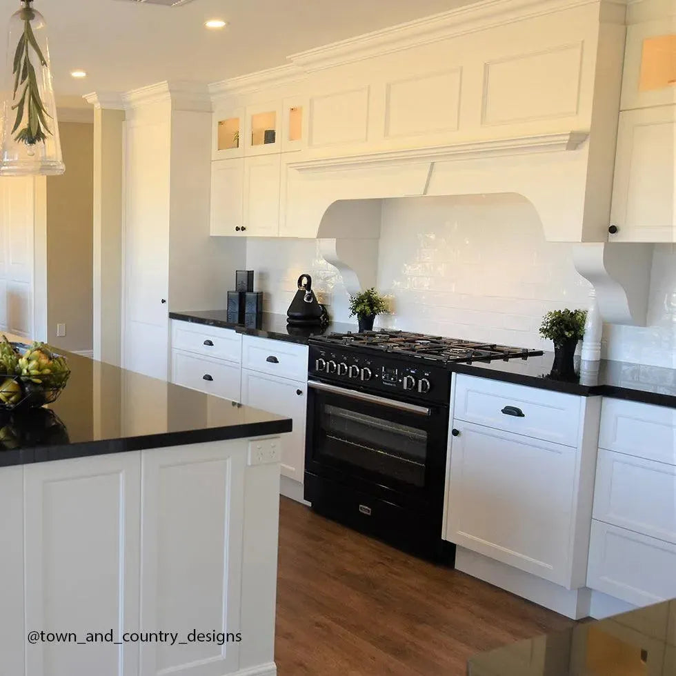 Elegant white kitchen with black range, island, and hardwood floors — designer appliances for modern homes