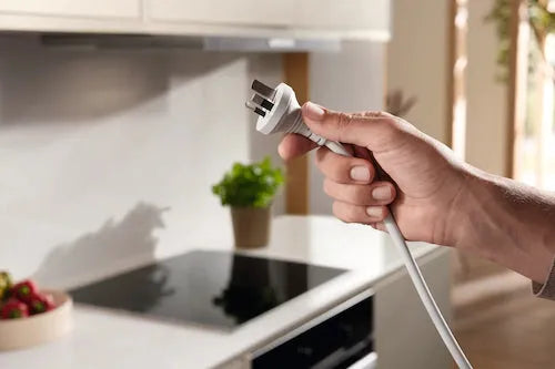 Hand plugging power cord into Falcon premium European glass black induction cooker