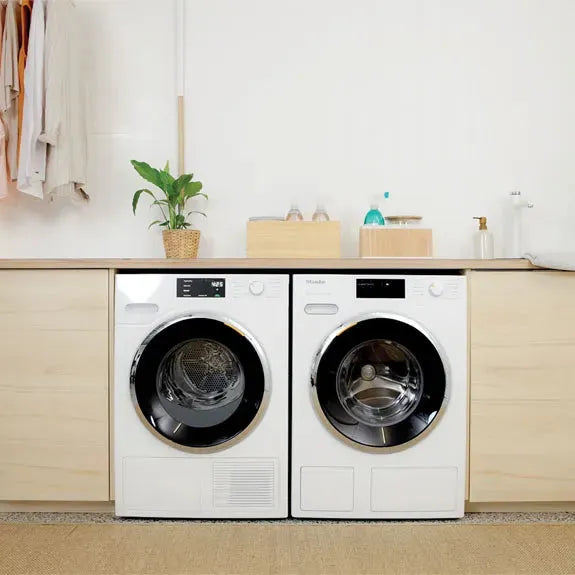 White front load washer and dryer set in modern laundry room with wood cabinets