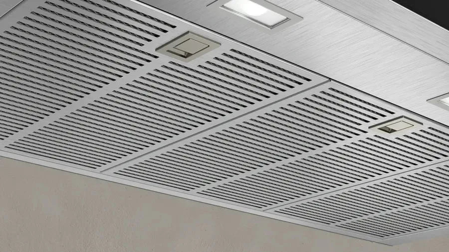 Stainless steel kitchen range hood with sleek grilles and integrated lighting
