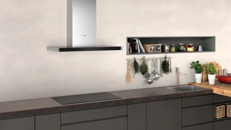 Modern kitchen with sleek stainless steel range hood, dark cabinets, and hanging herbs