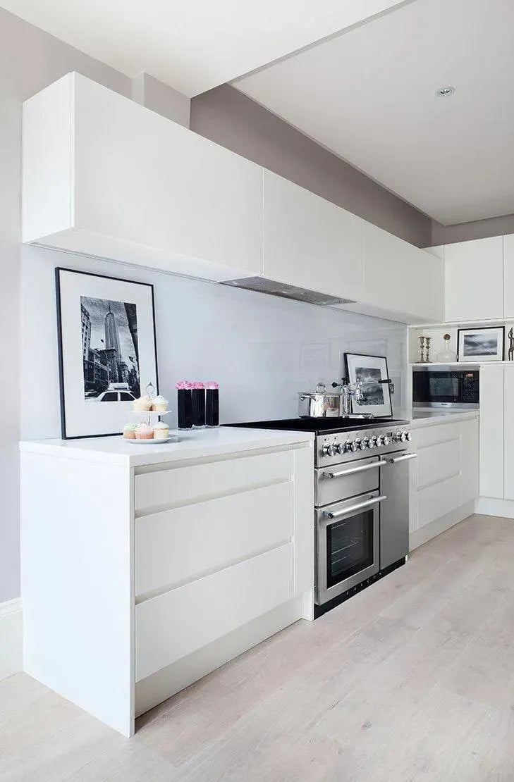 Modern white kitchen with stainless steel range oven and sleek cabinetry for designer appliance gallery