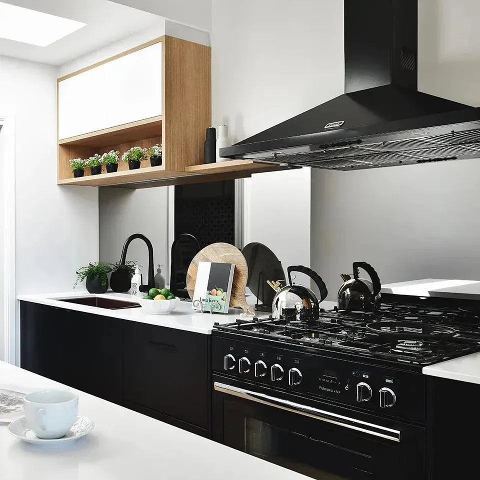 Modern black gas range with oven and range hood in sleek kitchen with white countertops
