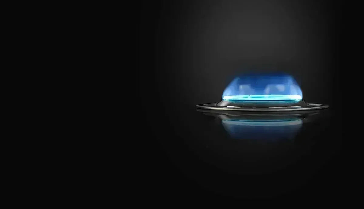 Blue flame gas burner on sleek black cooktop, modern kitchen appliance detail